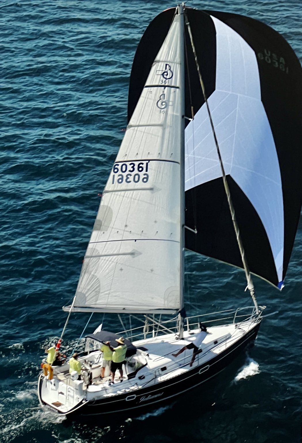 Black and white spinnaker sail over blue water